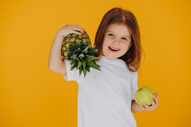 Cute little girl with pineapple and apple