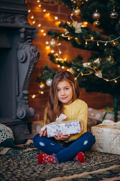 Милая маленькая девочка с подарками у елки