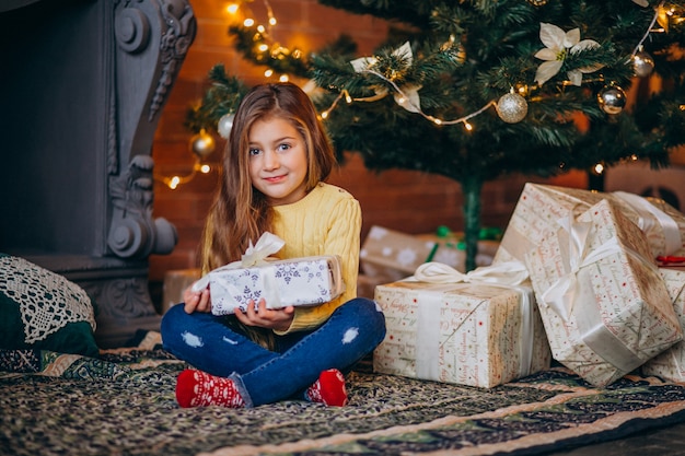 Cute little girl with presents by the Christmas tree