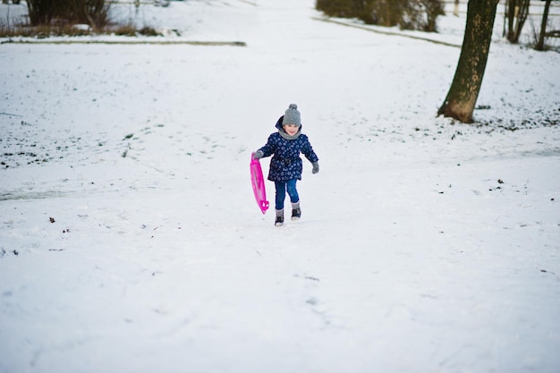 Cute little girl with saucer sleds outdoors on winter day