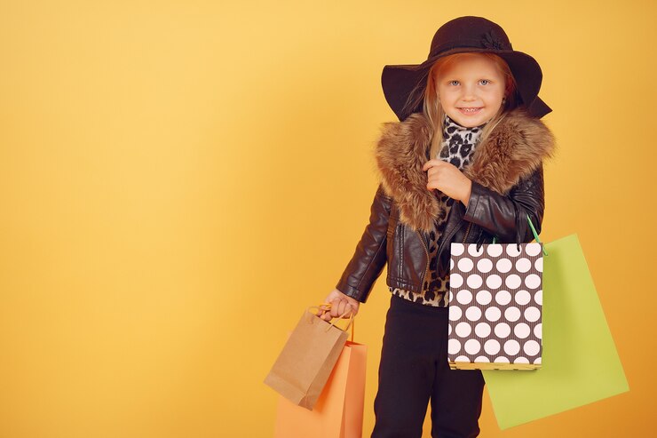 Free Photo cute little girl with shopping bags on a yellow background