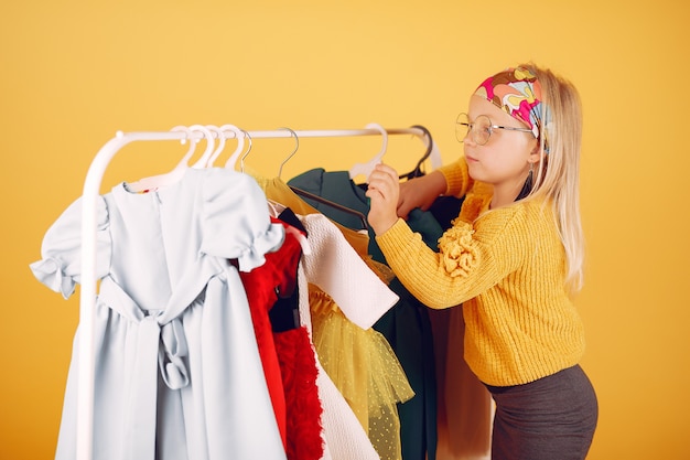 Cute little girl with shopping bags on a yellow background