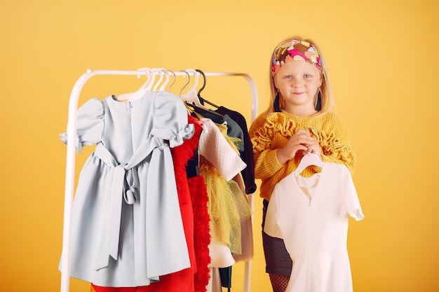 Cute little girl with shopping bags on a yellow background