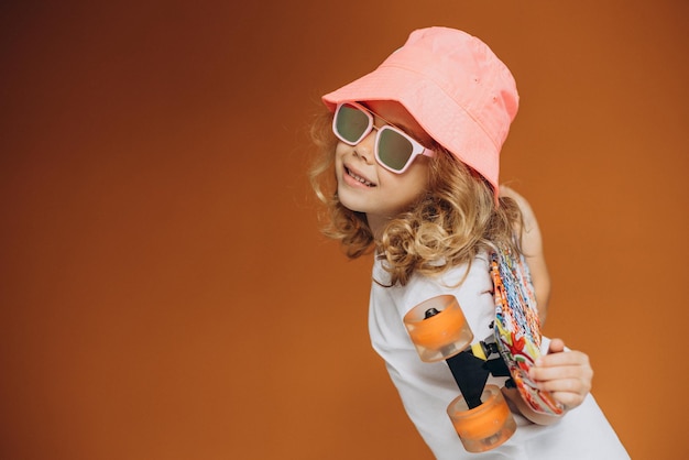 Free photo cute little girl with skate board isolated in studio