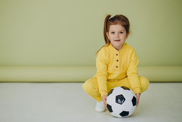 Cute little girl with soccer ball in studio