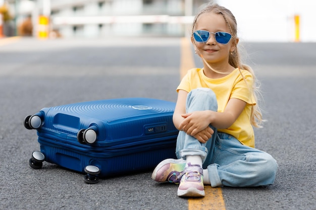 Бесплатное фото Милая маленькая девочка с чемоданом на открытом воздухе