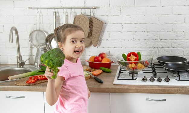 台所で野菜とかわいい女の子。健康的な食事とライフスタイルのコンセプト。家族の価値。