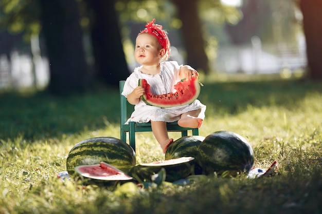 Free photo cute little girl with watermelons in a park