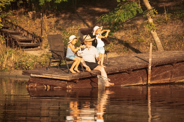 귀여운 소녀와 할아버지가 호수 나 강에서 낚시를하고 있습니다.