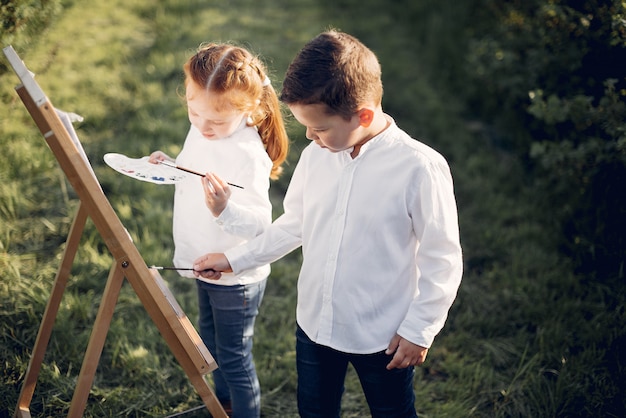 かわいい小さな子供たちが公園で絵を描く