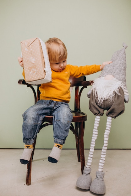 Cute little red hair boy sitting in chair with christmas toy