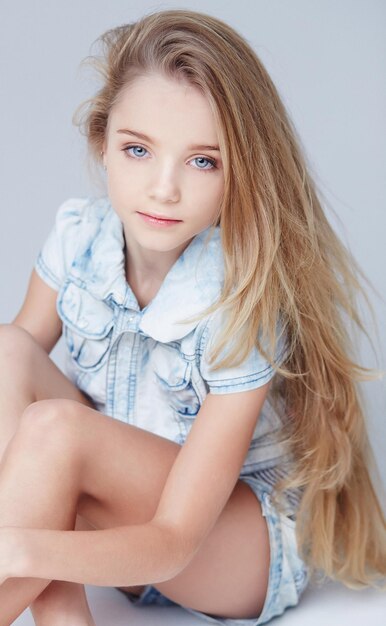 Cute long haired little girl posing in studio. Isolated on greu