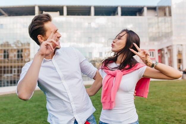 Cute loving couple fooling around during outdoor photoshoot in summer day