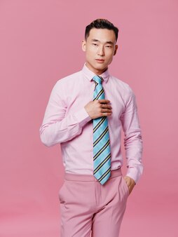 アジアの外観のかわいい男ピンクのシャツストライプネクタイピンクの背景