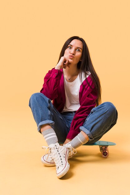 Cute model sitting on skateboard