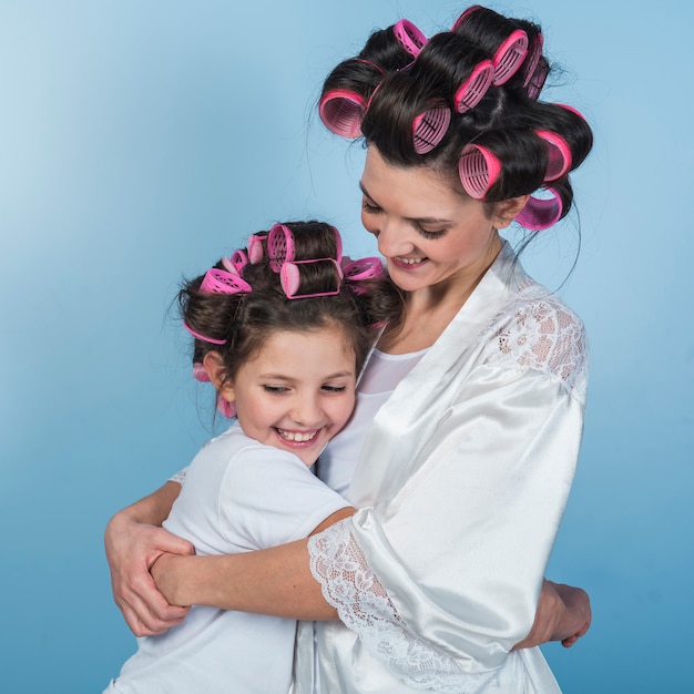 Free photo cute mother and daughter in curlers hugging