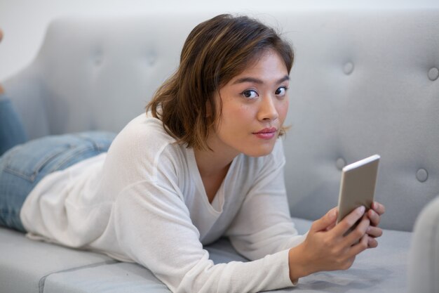 Cute pensive Asian girl browsing internet