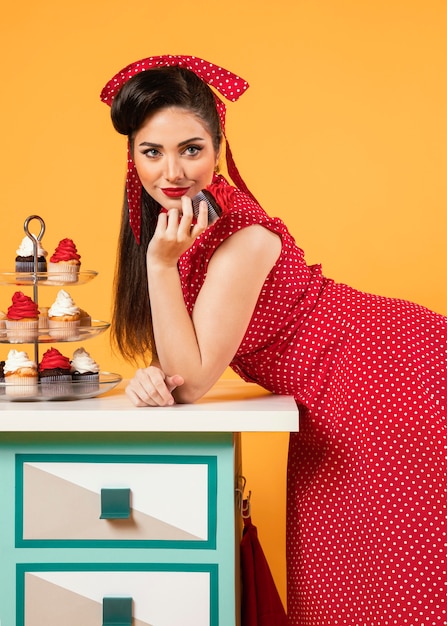 Free photo cute pinup girl standing next to some cupcakes