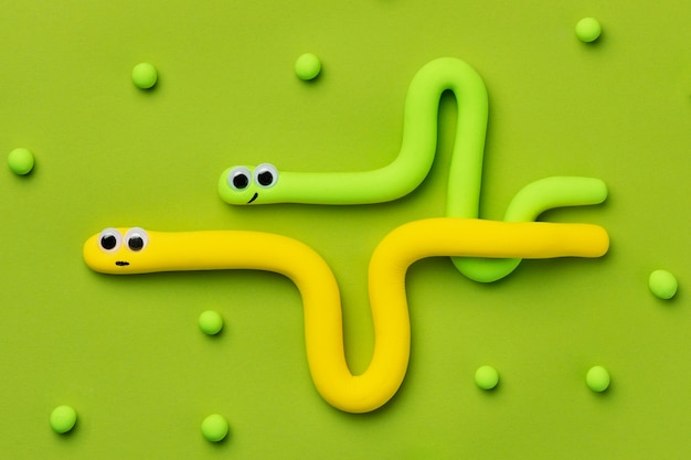 Симпатичные змеи из пластилина на зеленом фоне