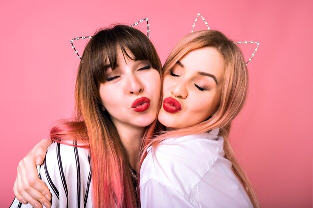 Cute positive portrait of happy pretty best friend sister women hugs smiling, trendy pink hairs, party cat ears, family look