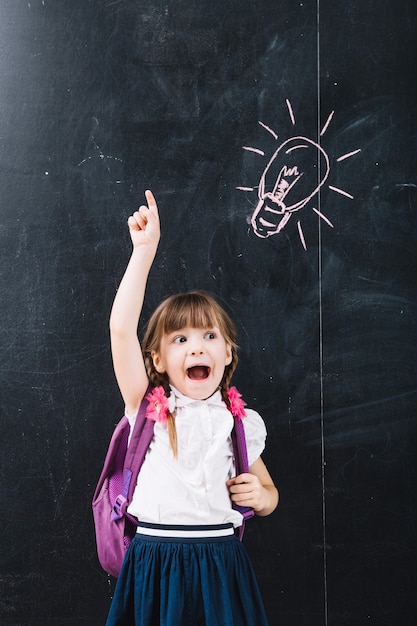 Cute pupil pointing up at blackboard