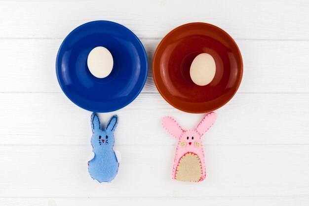 Cute rabbits near plates with eggs