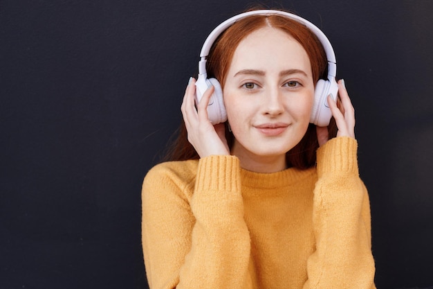 cute red hair woman in headphones outdoor in casual wear