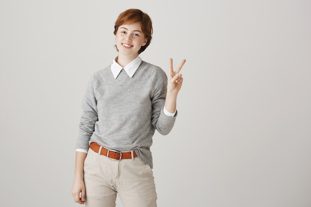 Cute redhead girl with short haircut posing against the white wall