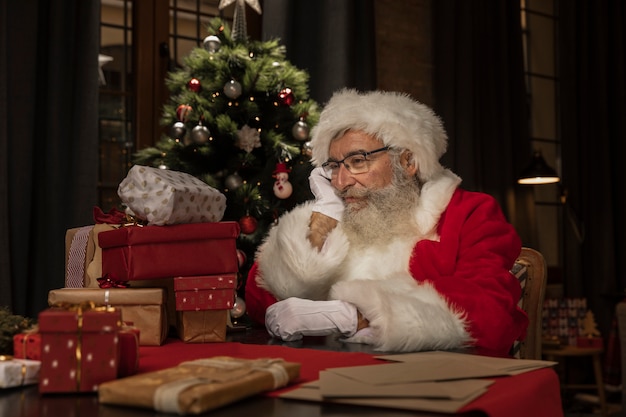 Free photo cute santa claus at the table thinking