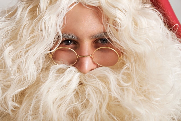 Free photo cute santa with greyish blue eyes and golden glasses, close up portrait