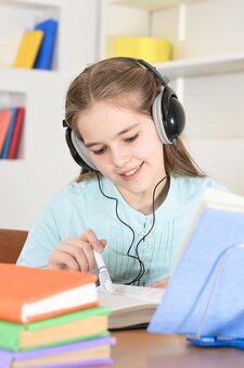 Cute schoolgirl in headphones  studying at home