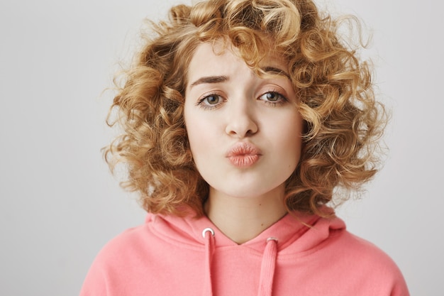 Free photo cute shy curly-haired girl folding lips trying to kiss