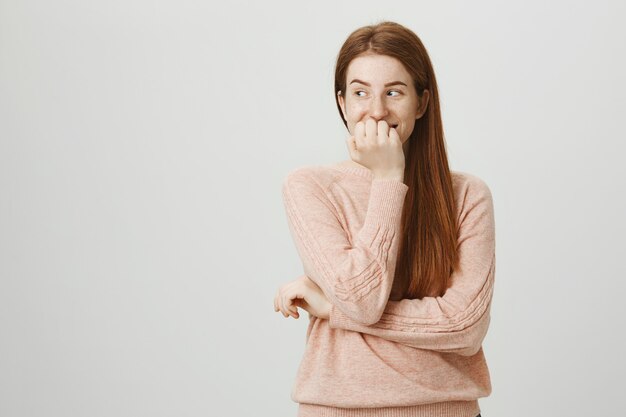 かわいい愚かな赤毛の10代の少女が笑い、広告を左に見て