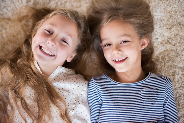 Free photo cute sister having fun on the fluffy carpet