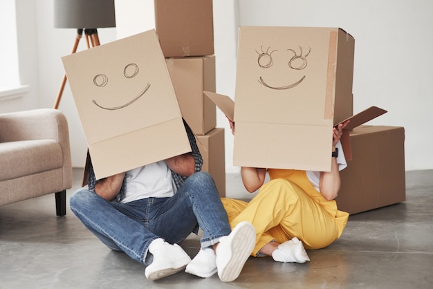 머리에있는 상자에 귀여운 미소. 그들의 새 집에서 함께 행복 한 커플입니다. 이사의 개념
