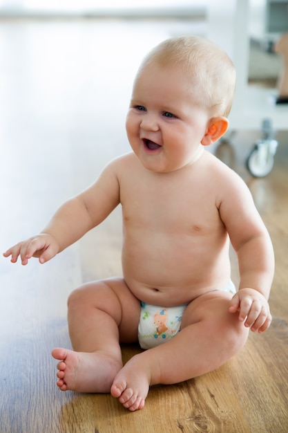 Cute smiling baby sitting at home.