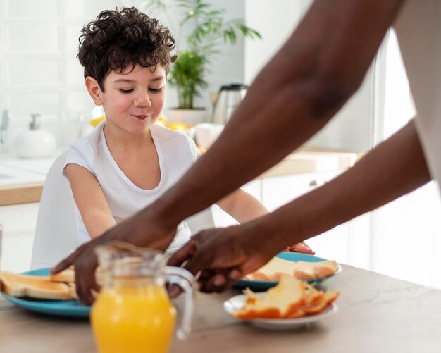 Cute smiling boy having breakfast with his dad