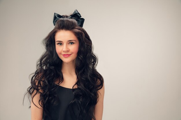 Cute smiling. Portrait of beautiful young woman on grey studio