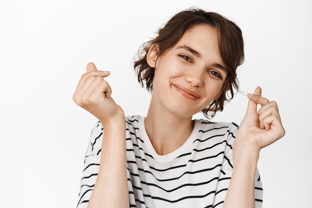 Foto gratuita carina donna sorridente che mostra i cuori delle dita, guardando abiti bianchi e casual.