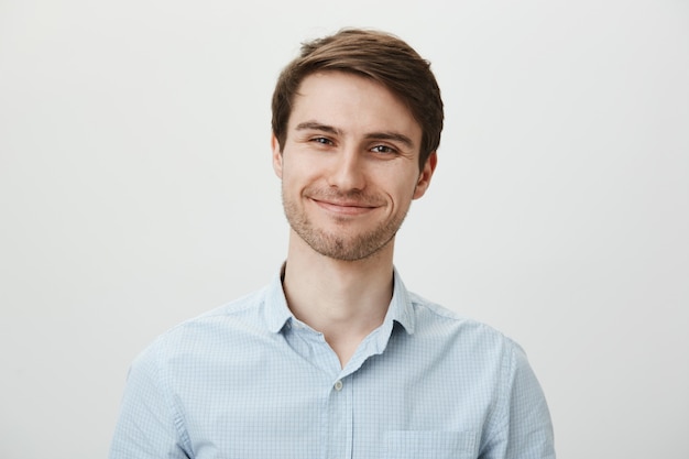 Cute smiling young man with bristle looking satisfied