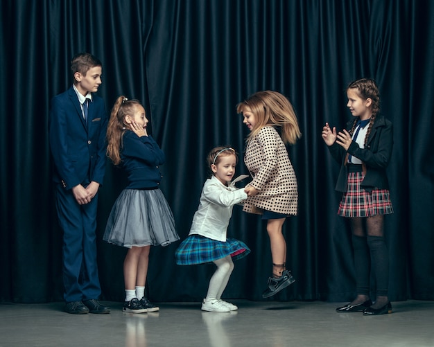 Free photo cute stylish children on dark  space. the beautiful teen girls and boy standing together