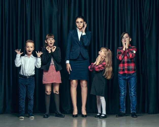 어두운 스튜디오 배경에 귀여운 세련된 어린이. 아름 다운 십 대 소녀와 함께 서있는 소년