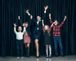 Free photo cute stylish children on dark studio background. the beautiful teen girls and boy standing together