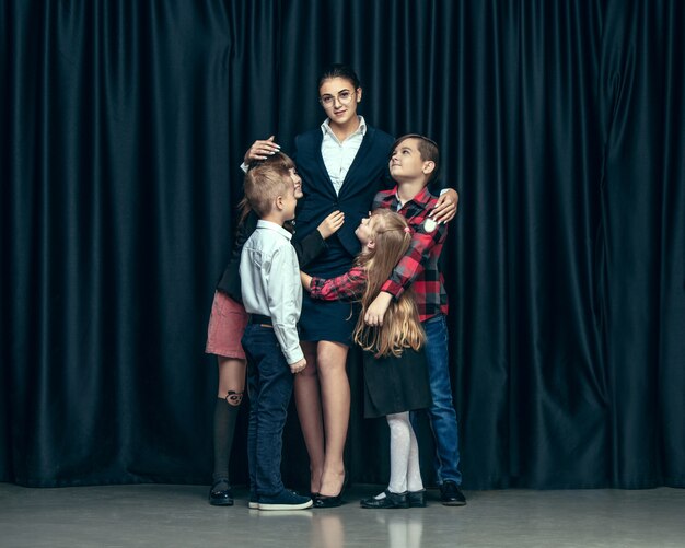 Cute stylish children on dark studio. The beautiful teen girls and boy standing together