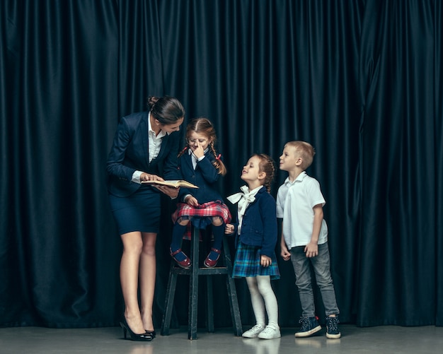 Cute stylish children on dark studio. The beautiful teen girls and boy standing together