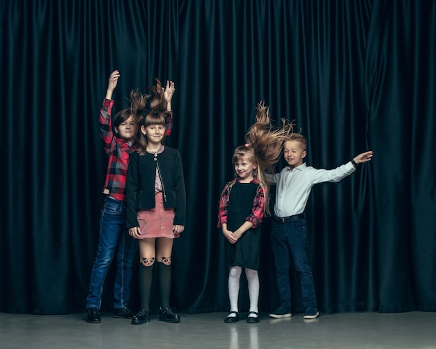 어두운 스튜디오에 귀여운 세련된 어린이. 아름 다운 십 대 소녀와 함께 서있는 소년