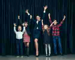 무료 사진 어두운 스튜디오 배경에 귀여운 세련된 어린이. 아름 다운 십 대 소녀와 함께 서있는 소년