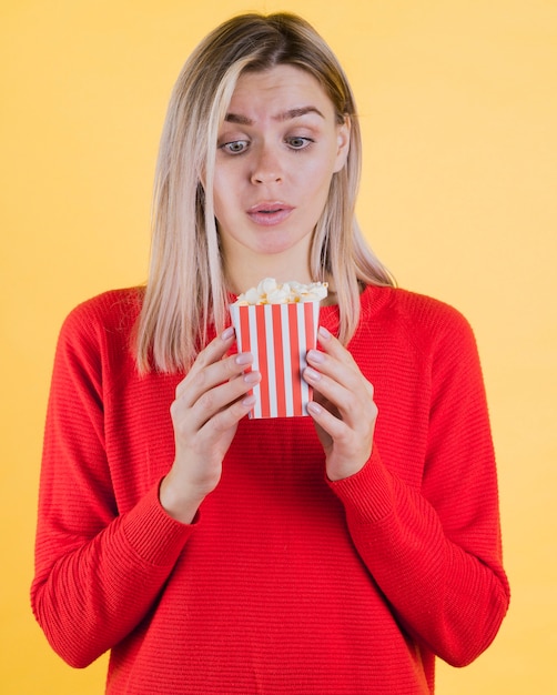 Cute surprised woman holding popcorn bag