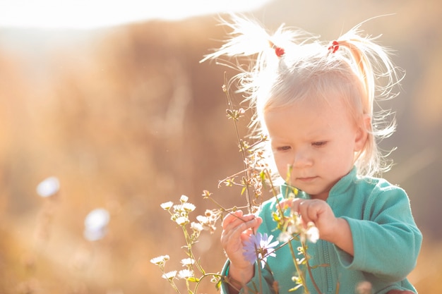 Foto gratuita bambina carina e dolce che gioca con i fiori all'aperto
