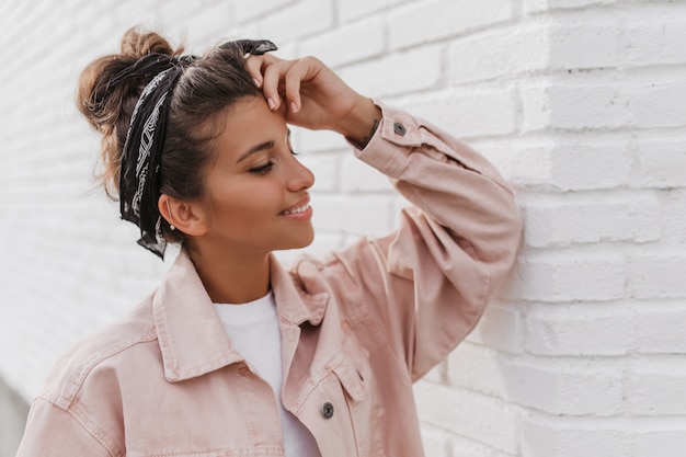 Cute tanned woman with bun and in headband smiles